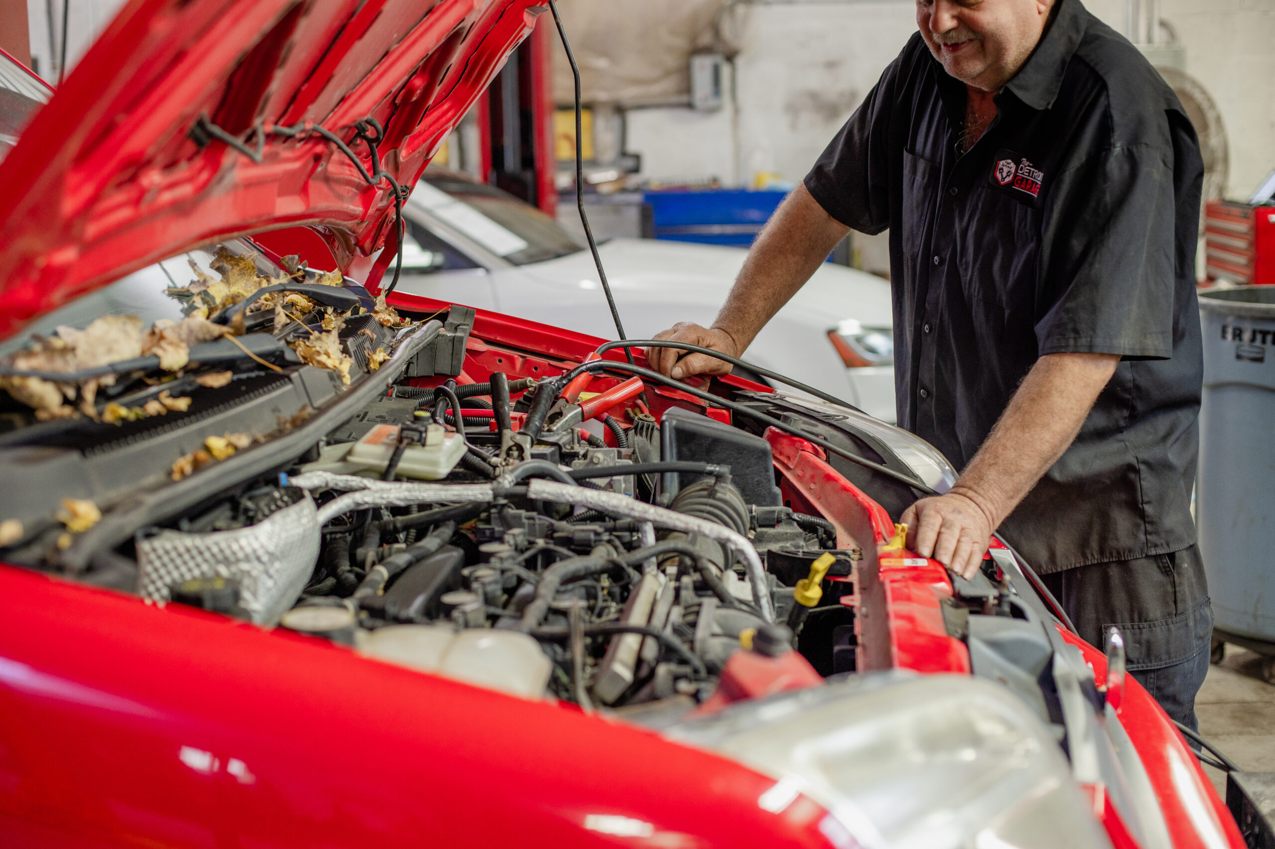 Car technician inspecting under the hood of a car.