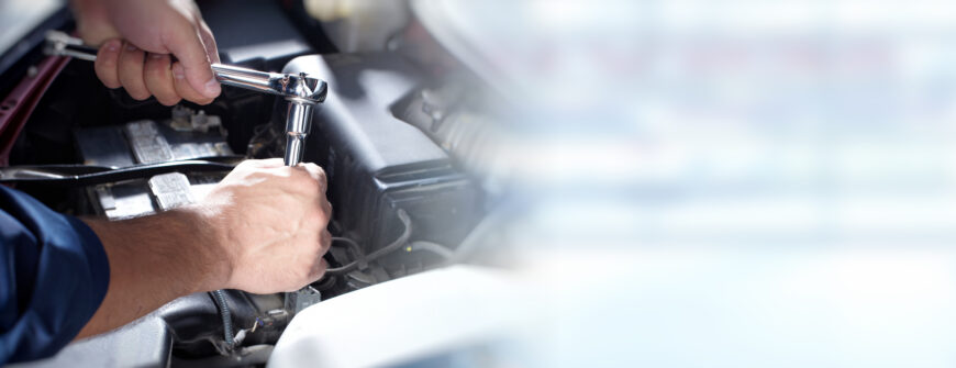 Hands of car mechanic with wrench in auto repair service.